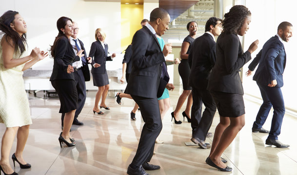 Businessmen And Businesswomen Dancing In Office Lobby