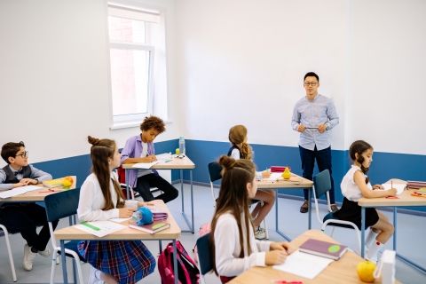 Teacher standing and talking to class of students sitting at desks