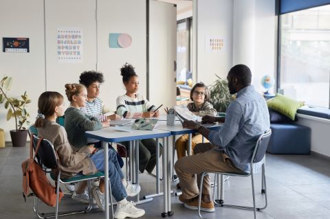 Students and teacher sitting around a table