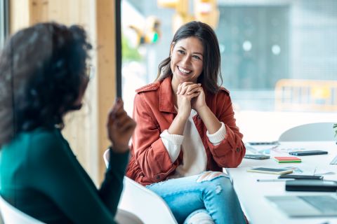 Two women at an office talking and smiling