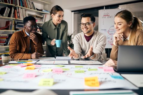 Colleagues sitting at a table talking and working on a poster with post-it notes